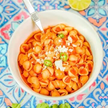 shell soup in a white bowl garnished with cheese and peppers