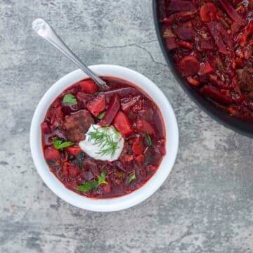 Ukrainian borscht recipe in a white bowl with more in a pot